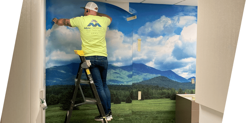 A man installing a wrap on a wall, showcasing his artistic talent and creativity in the installation process.